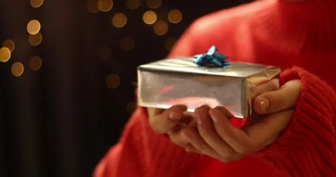 Close up of hands holding a silver gift box with a blue bow, festive bokeh Stock Footage 339071498