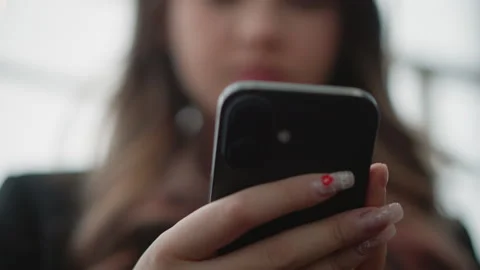 Close-up hands holding smartphone with decorated fingernails, thumb poised for Stock Footage 346628581