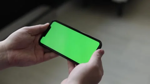 Close-up of hands holding a smartphone with a green screen for editing Stock Footage 339215089