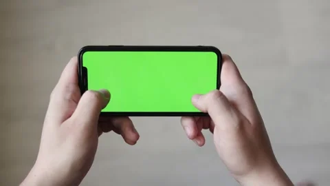 Close-up of hands holding a smartphone with a green screen in landscape mode Stock Footage 339217405