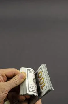Close-up of hands holding a stack of $100 bills. Stock Photos