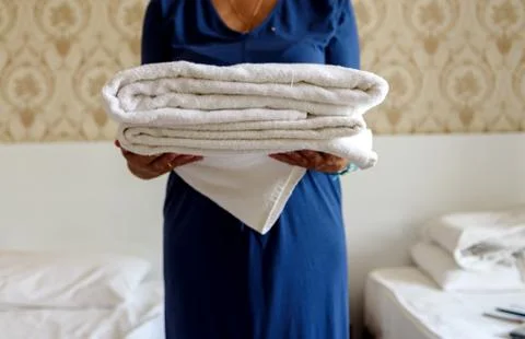 Close-up of hands holding a stack of fresh white bath towels. Stock Photos
