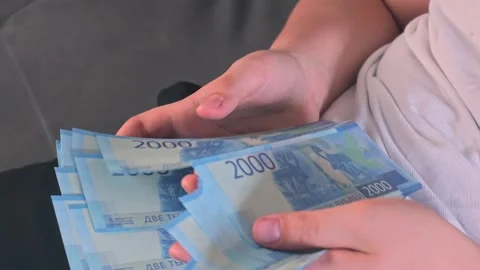 Close-up of hands holding a stack of Russian 2000 ruble banknotes. Blue money, c Stock Footage 347964656