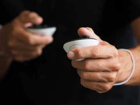 Close-up of hands holding white controllers, plays in virtual or mixed reality. Stock Photos