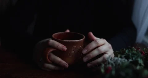 Close-up hands hug a brown ceramic mug on a wooden table Stock Footage 129709336