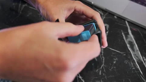 Close-up of hands inserting batteries into action camera compartment with Stock Footage 333650402