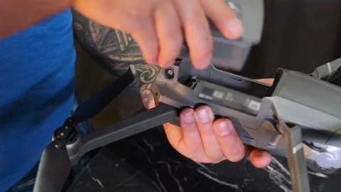 Close-up of hands inserting battery into drone compartment, preparing UAV for Stock Footage 333649507