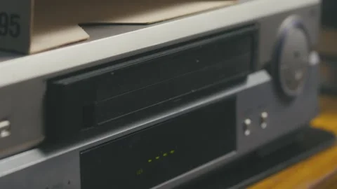 Close-up of hands inserting VHS cassette tape into video player Stock Footage 313462784