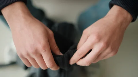Close up hands inspecting black woven fabric texture and detail in calm indoor Stock Footage 346659146
