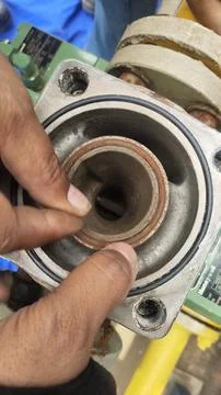 Close-up of hands inspecting a mechanical component in an industrial setting. Stock Photos