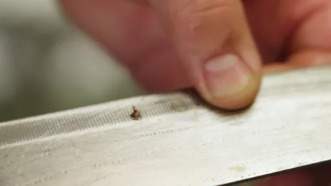 Close-up of hands inspecting rust spots on a dull knife in Malaysia, examining Stockbeeldmateriaal 333264150