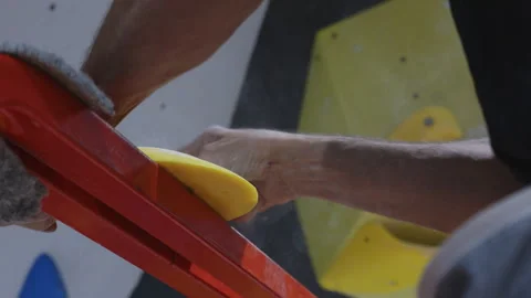 Close-up of hands installing a climbing hold on an indoor wall, showcasing the Stock Footage 277149020