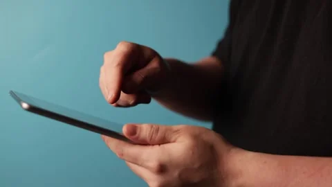 Close-up of hands interacting with a tablet computer on a blue background Stock Footage 340268249