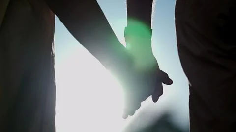 Close up of hands joining together with sunlight flare in the background. B.. Stock Photos