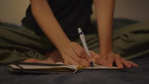 Close-Up Hands Journaling On Bed, Representing Self-Reflection 動画素材 337972024