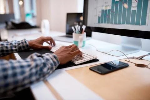 Close up of hands on a keyboard with graphs on computer screen Stock Photos