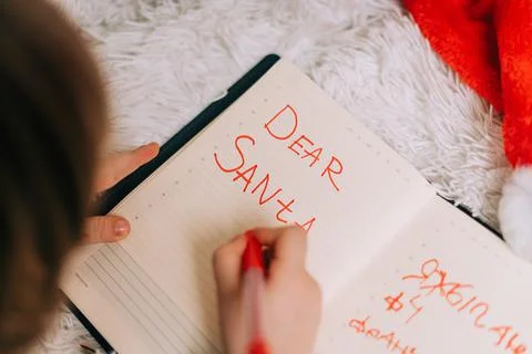 Close up hands of Kid boy, lying on couch and writing letter in note pad to dear Stock Photos