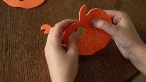 Close up on hands of a kid preparing orange pumpkin decoration for Halloween Stock Footage 253489764