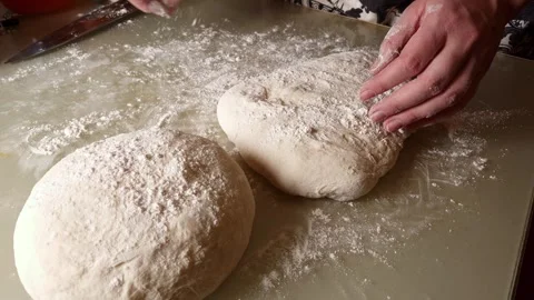 Close-up of hands kneading dough on a floured kitchen table in slow motion Stock Footage 330761417
