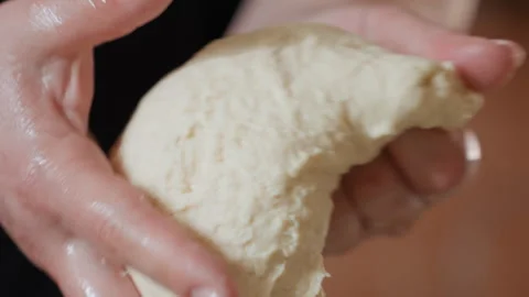 Close-up hands kneading raw dough with elastic stretching, folding, squeezing Stock Footage 343676420
