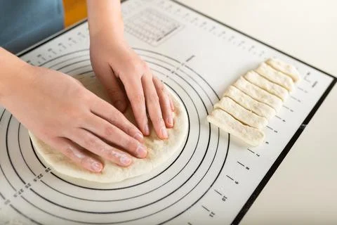 Close-up of hands kneading rolled out dough on a kitchen baking mat with round Stock Photos