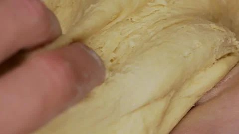 Close-up of hands kneading soft dough, fingers covered in flour, pressing and Stock Footage 303889501