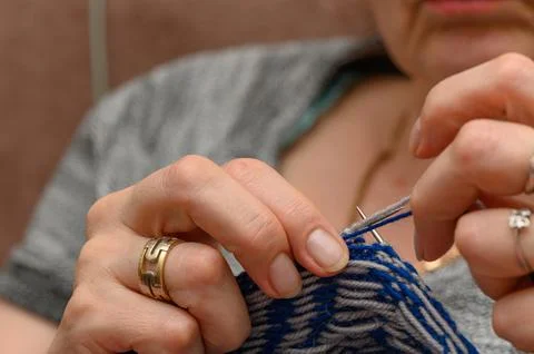 Close-up of hands knitting jacquard pattern with blue and grey yarn Fotos de archivo
