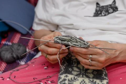 Close-up of hands knitting a patterned wool sock with multiple needles Stock-Fotos