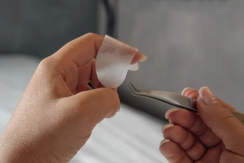 Close up of hands of lashmaker holding thin patch on finger and preparing to  Stock Photos