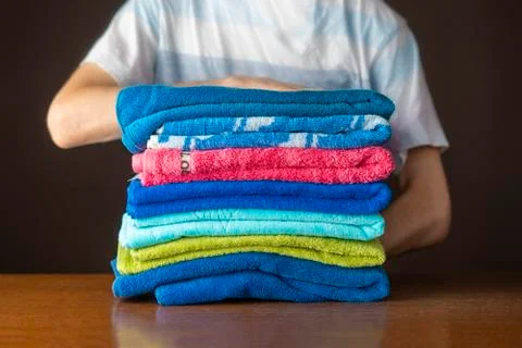 Close up hands lay down stack of clean towels on table Stock Photos