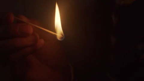 Close-up of Hands Lighting Match with Bright Flame in Dark Room 库存影片 334643741