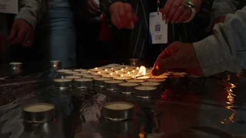 Close-up of hands lighting memorial candles with matches. Group ceremony with Stock Footage 304727735