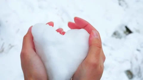 Close-up hands made a heart out of snow and broke it. The heart is made of snow. Video stock 221895422