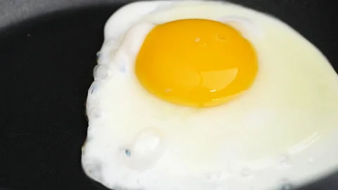 Close up of hands making fried eggs in black frying pan. Breakfast concept. Stock Footage 140253684
