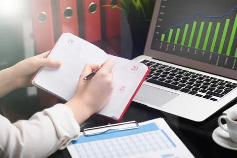 Close-up of hands making notes in diary next to tablet computer 스톡 사진
