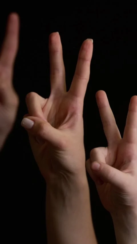 Close-up of hands making peace and victory gesture with two fingers up on black 動画素材 347461013