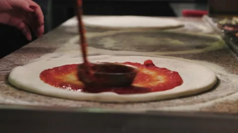 Close up of hands making pizza. The cook pours the sauce on the pizza Stock Footage 232395855