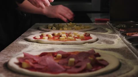 Close up of hands making pizza. The cook puts cheese, meat sausages on the pizza Stock Footage 232410389