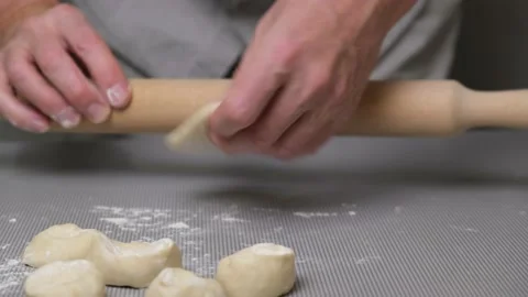 Close-up of the hands of a male chef rolling out dough with a rolling pin. Stock Footage 166035239