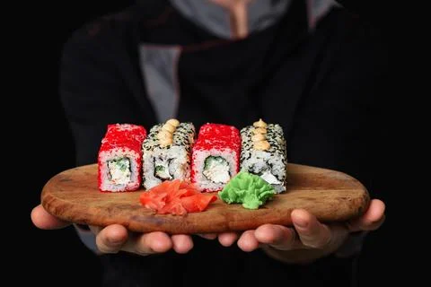 Close-up of the hands of a Man chef in a black uniform holding a wooden tray Foto stock