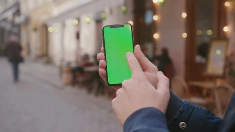 Close-up hands of man holding and using vertical mobile phone with green screen Stock Footage 117428808