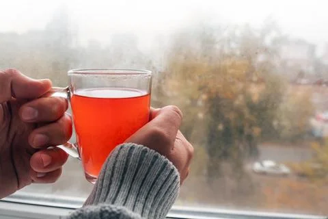 Close-up of the hands of a man holding a cup of tea by the window. Stock Photos