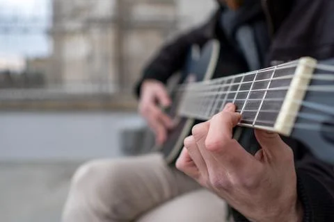 Close-up of the hands of a man learning to play the guitar alone in the stree Foto stock
