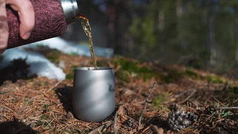 A close-up on the hands of a man pouring hot tea from a thermos into a metal mug Stockbeeldmateriaal 276729786