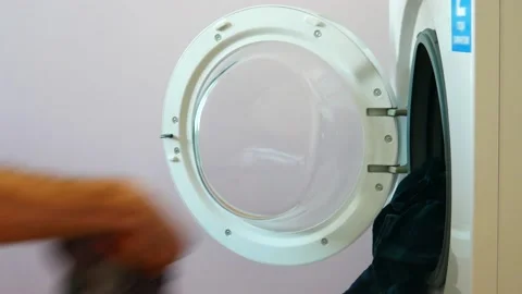 Close-up of the hands of a man putting clothes in the washing machine Stock Footage 169881102