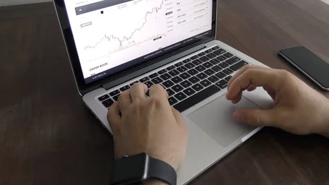 Close up hands of a man typing on keyboard at the desk and watches chart cripto Stock Footage 82491159