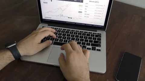 Close up hands of a man typing on keyboard at the desk and watches chart cripto Stock Footage 82498524