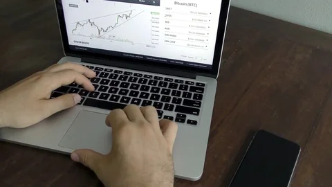 Close up hands of a man typing on keyboard at the desk and watches chart cripto Stock Footage 82501041