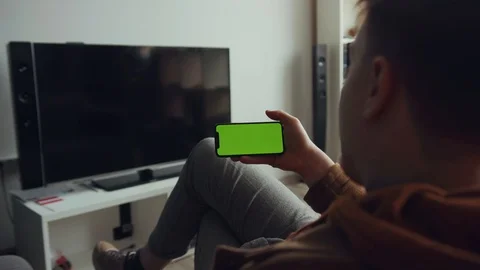 Close up hands man use phone with green screen sitting sofa waving his hand in Stock Footage 105203821