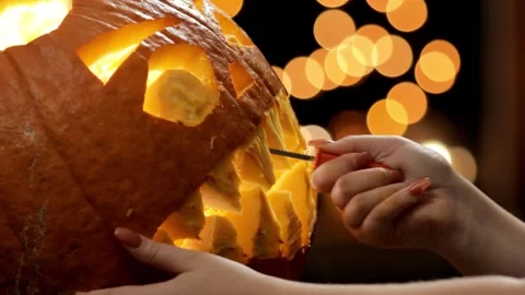 A close-up of the hands of a man using knife to cut out a funny face from a Stock Footage 272462110